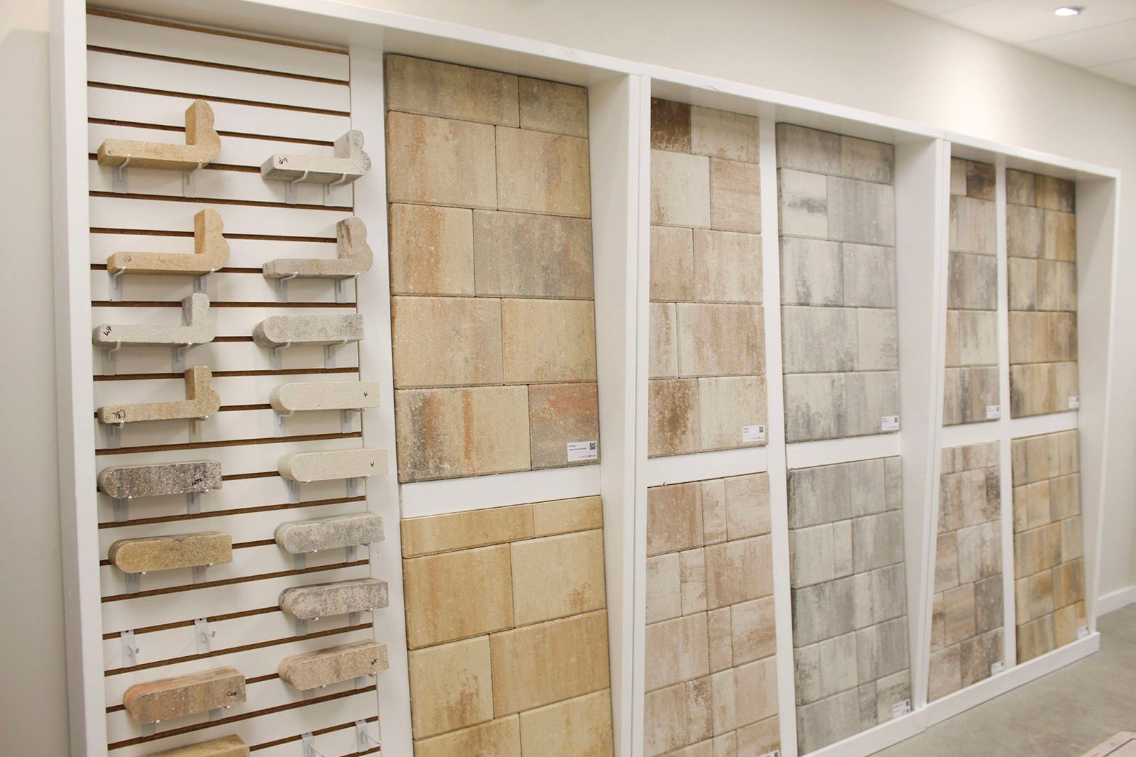 Wall display of stone and tile samples in a showroom, arranged in white framed panels