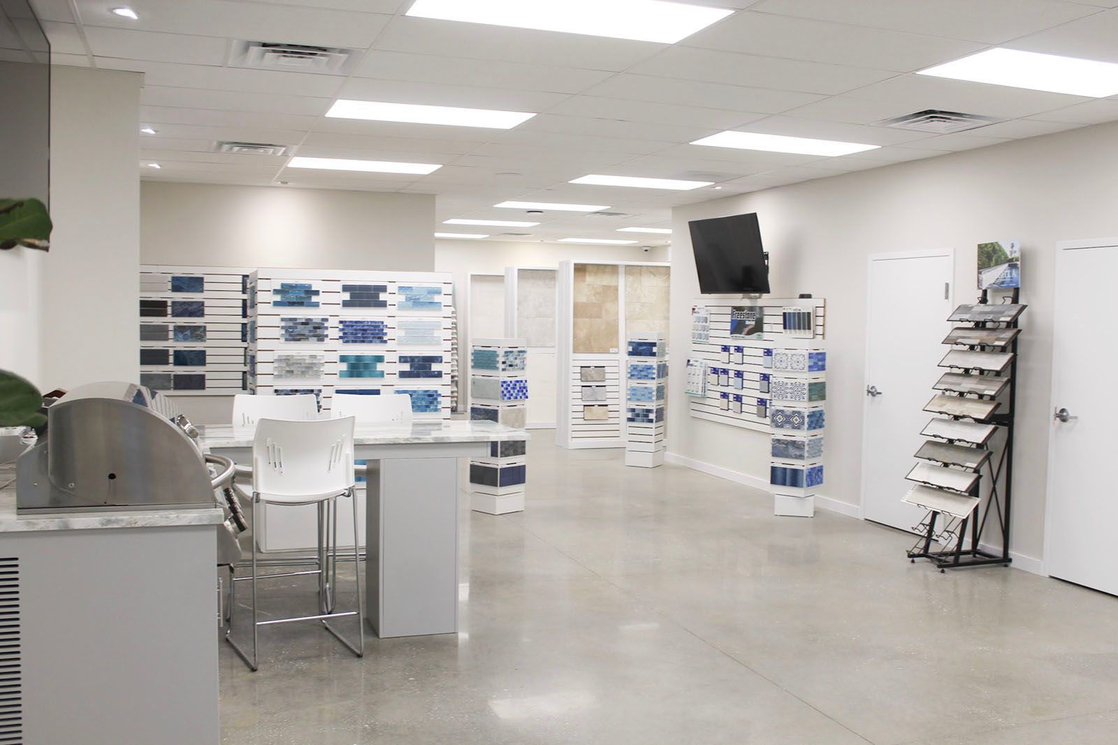 Bright showroom with displayed tile samples and a wall-mounted TV