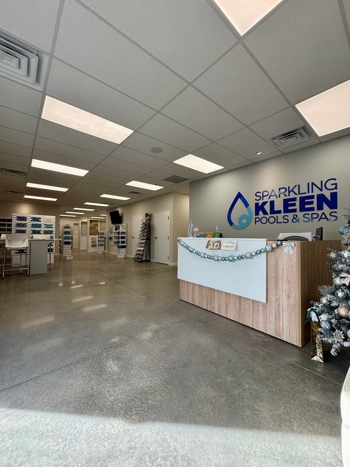 Swimming pool with light blue water and stone patio. Two white chairs in the background.