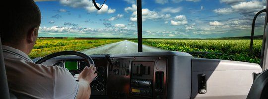 A man is driving a truck down a country road.
