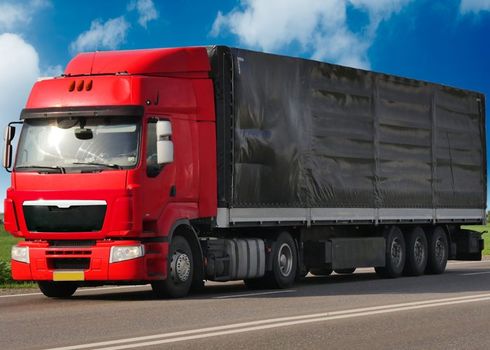 A red semi truck is driving down the road