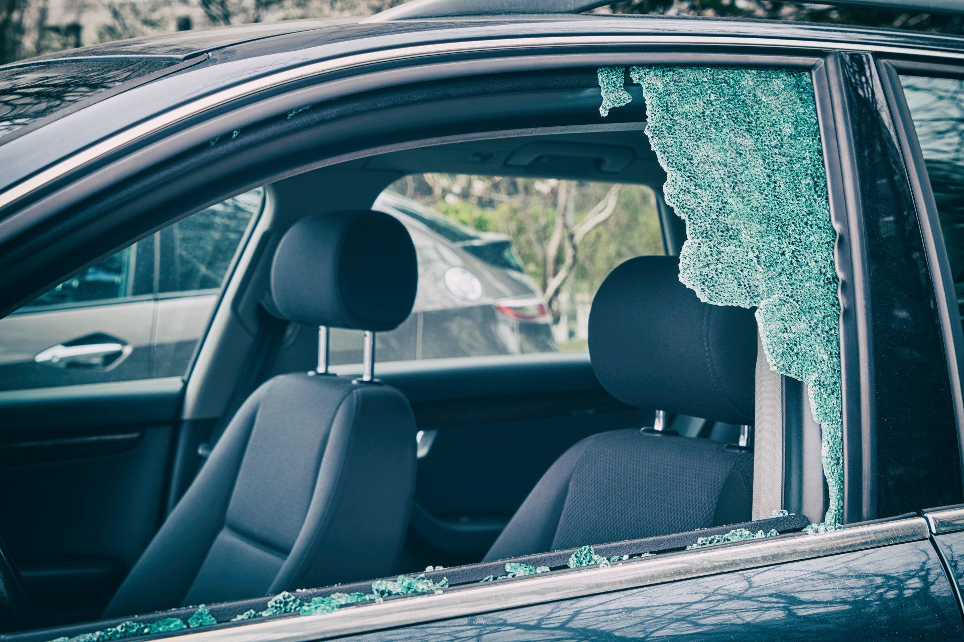A car with a broken windshield is parked in a parking lot.