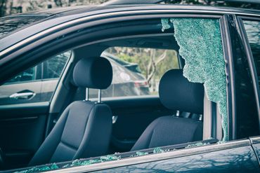 A car with a broken windshield is parked in a parking lot.