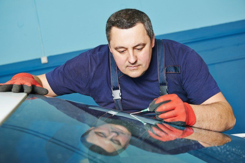 A man is repairing a windshield on a car.