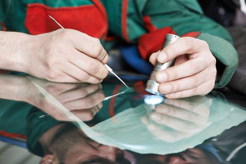 A man is working on a windshield with a tool