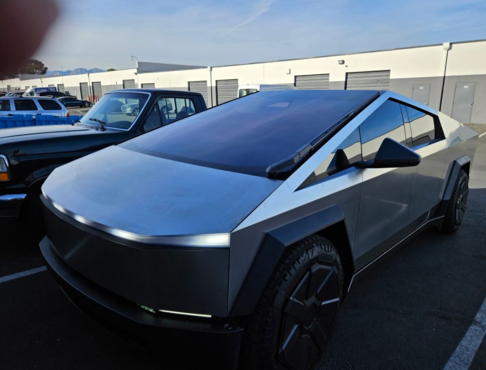 A silver tesla cybertruck is parked in a parking lot