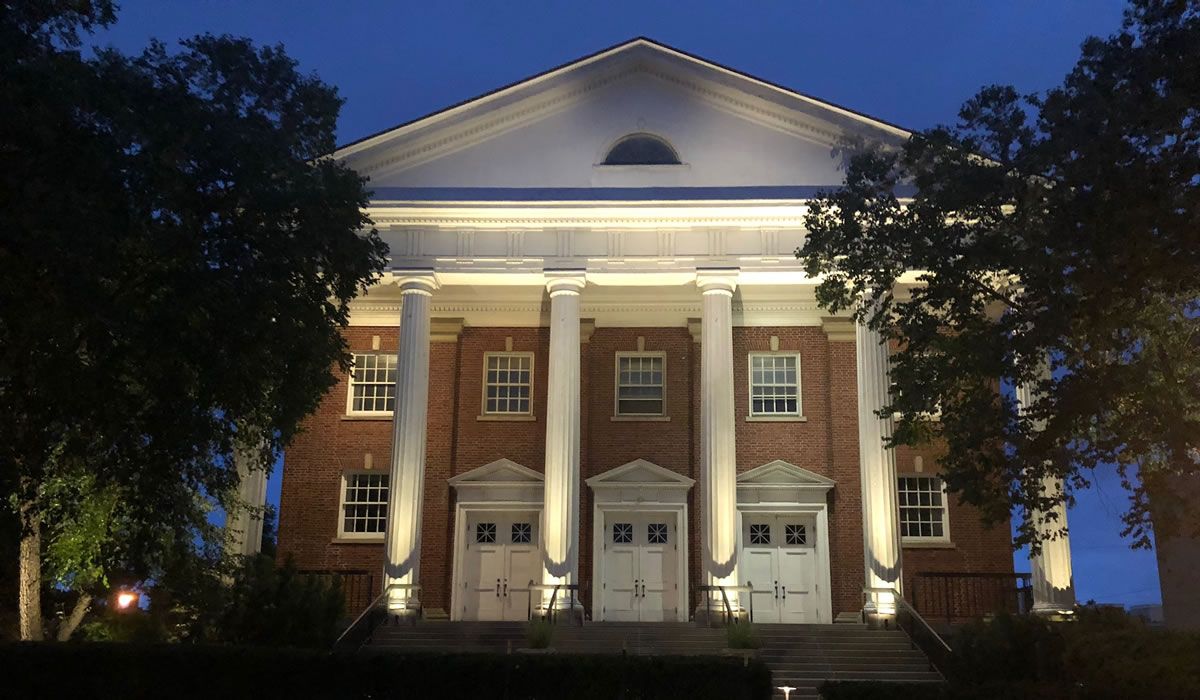 A large brick building with columns is lit up at night.