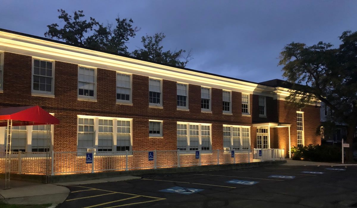 A large brick building with a lot of windows is lit up at night.