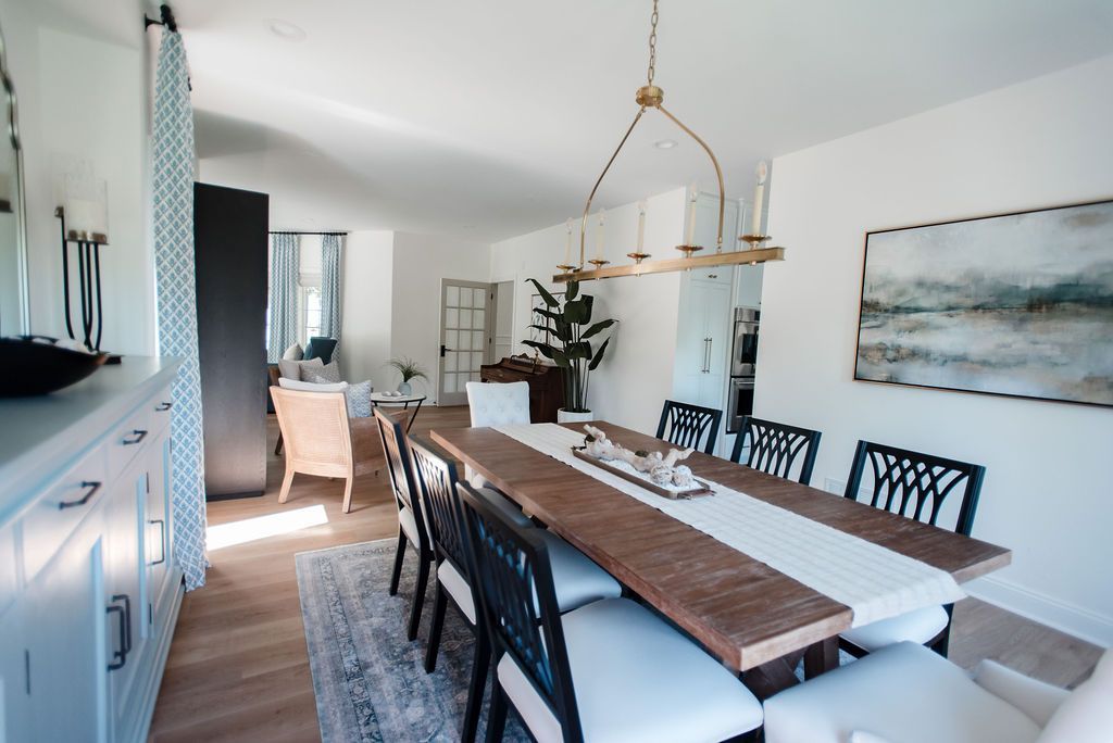 Bright dining room with black chairs, wooden table, and coastal wall art