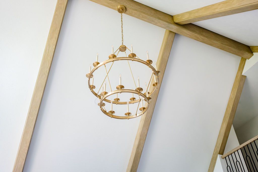 Gold chandelier hanging from a white vaulted ceiling with gold trim.