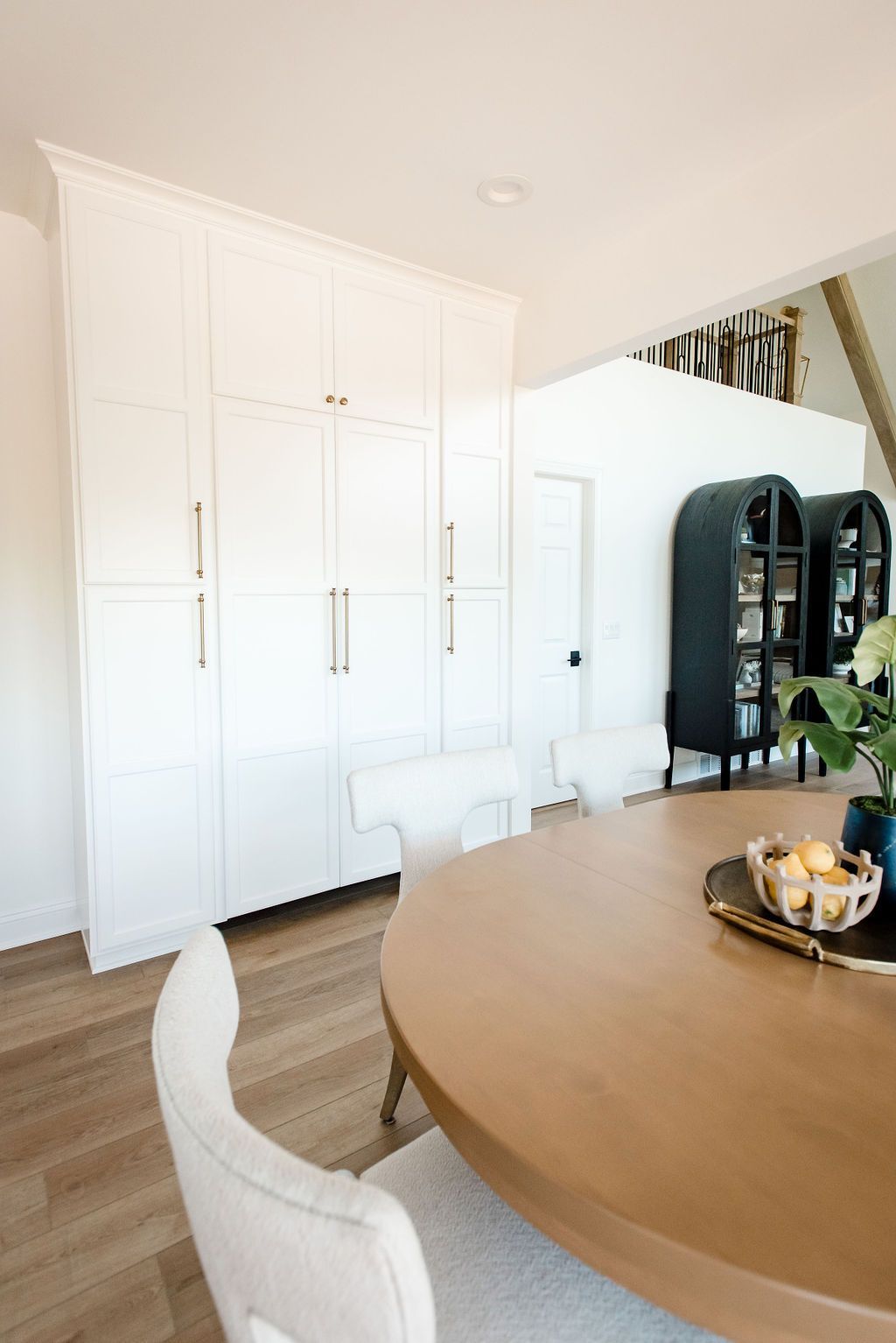 Bright dining room with white built-in cabinets, wood table, and black glass display cabinet