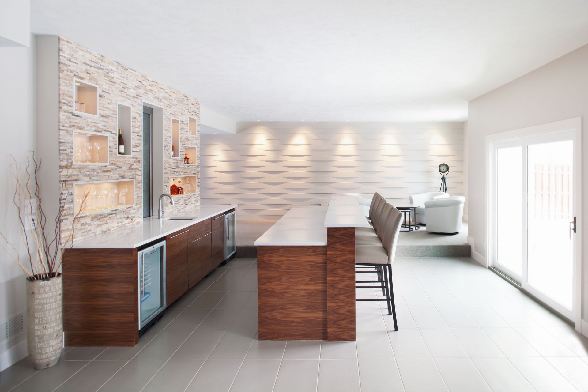 Bright modern kitchen and dining area with island, stone accent wall, and white tile floors