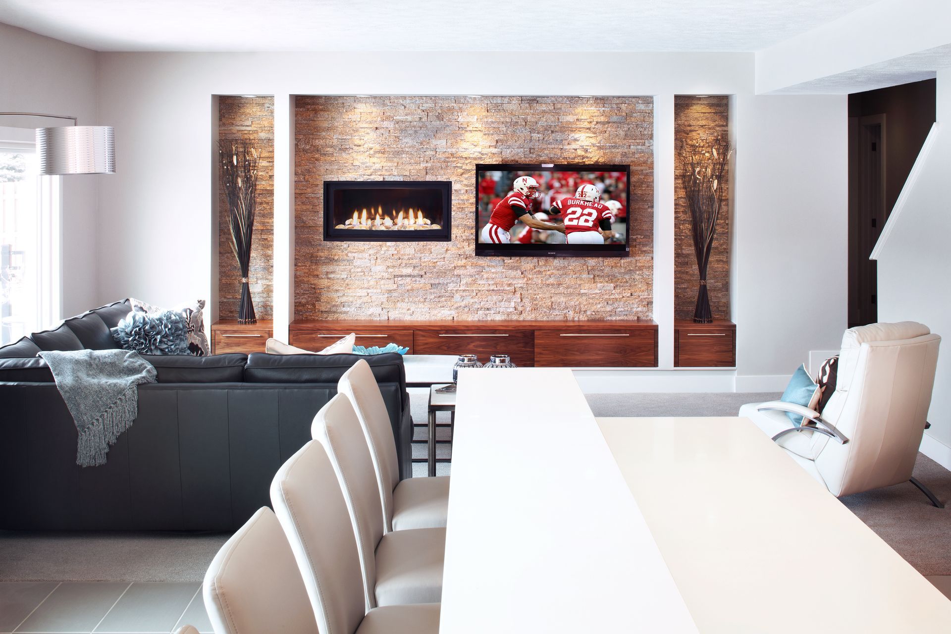Modern open-plan living room with a fireplace, TV, sectional sofa, and long dining table