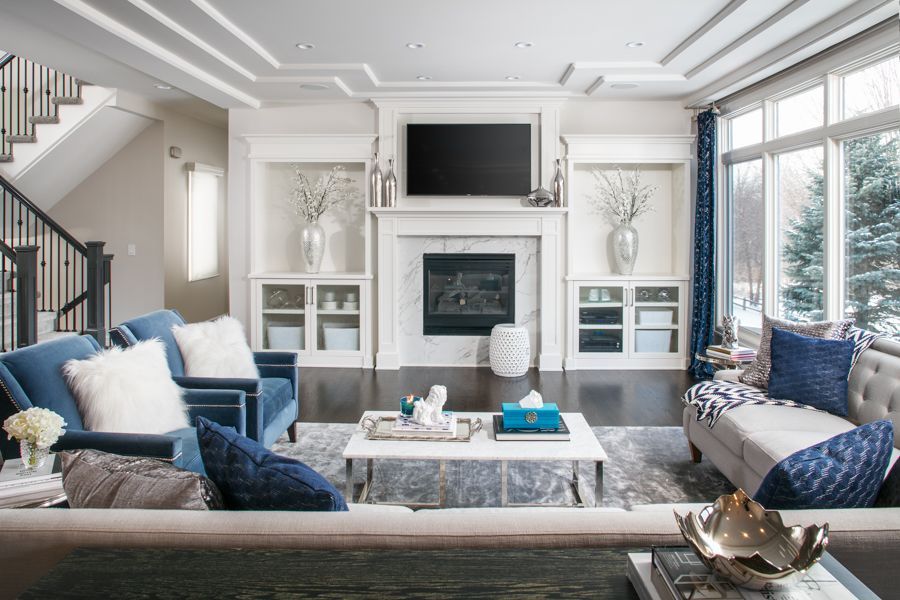 Bright modern living room with blue sofas, white fireplace, and large windows