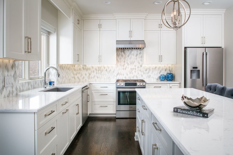 Bright white modern kitchen with island, stainless steel appliances, and dark wood floors