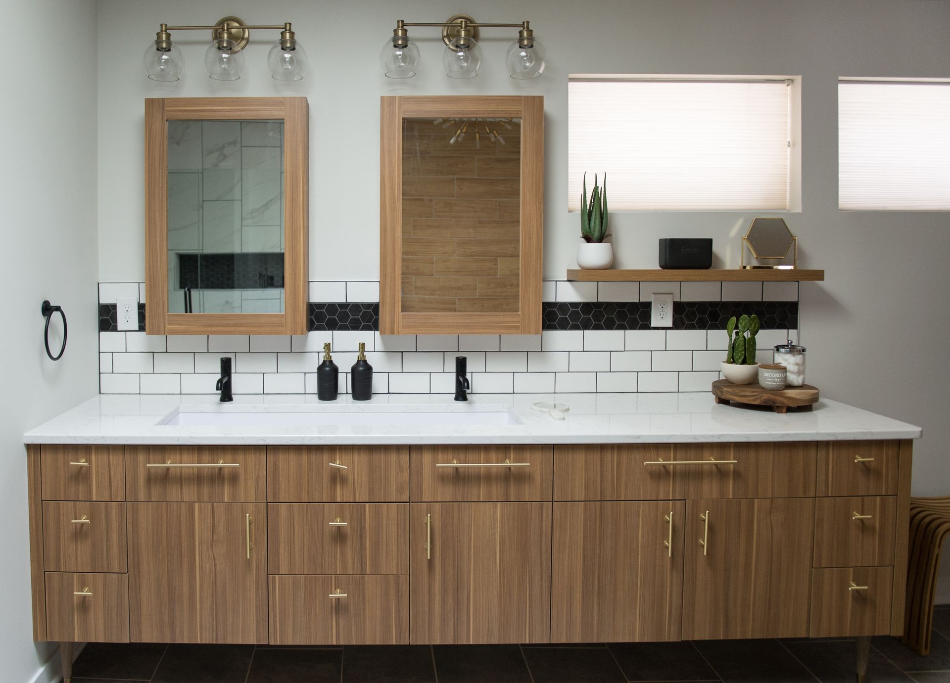 Modern bathroom vanity with double wood-framed mirrors, white tile backsplash, and black fixtures