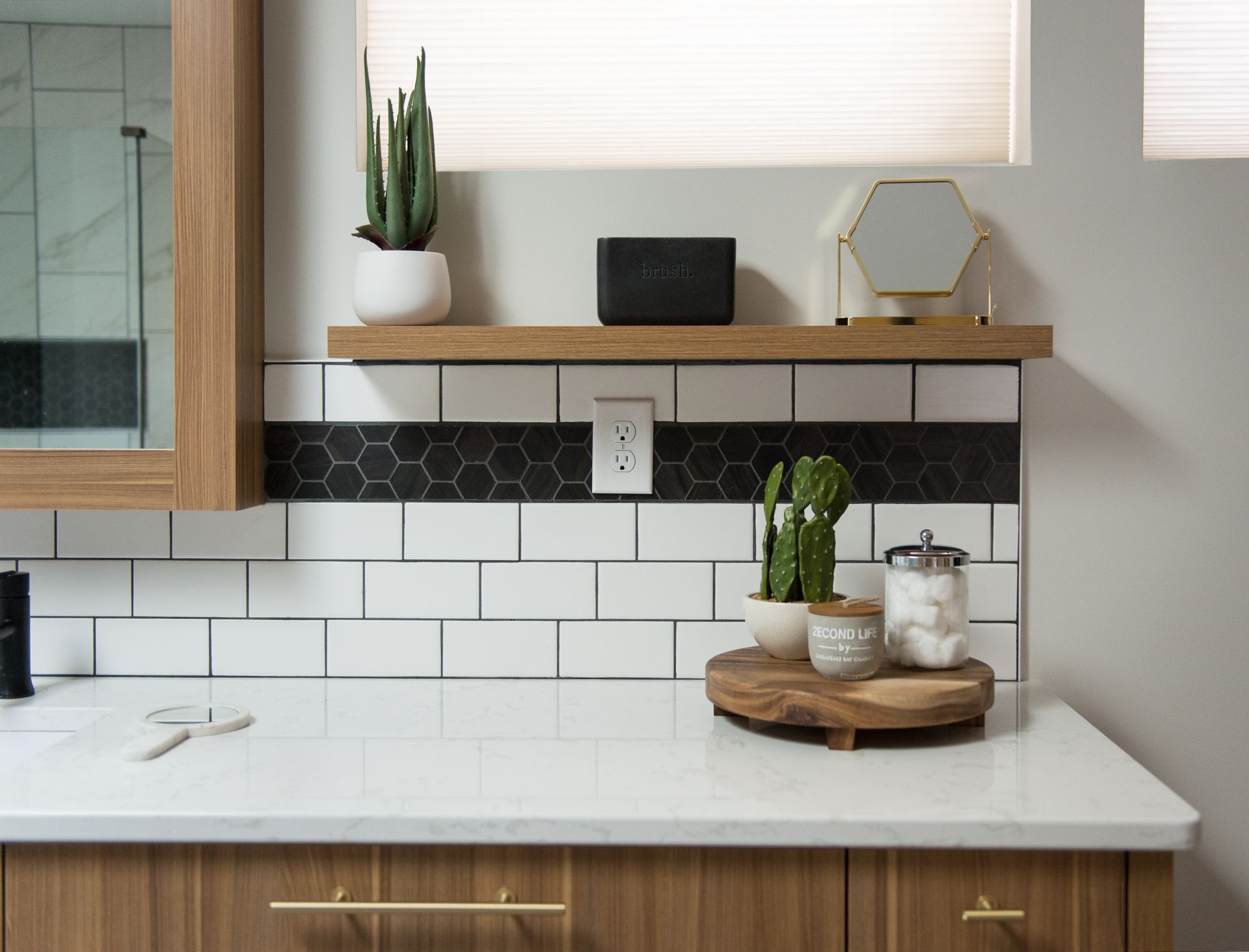 Modern kitchen counter with white tile backsplash, wood shelves, plants, and decor
