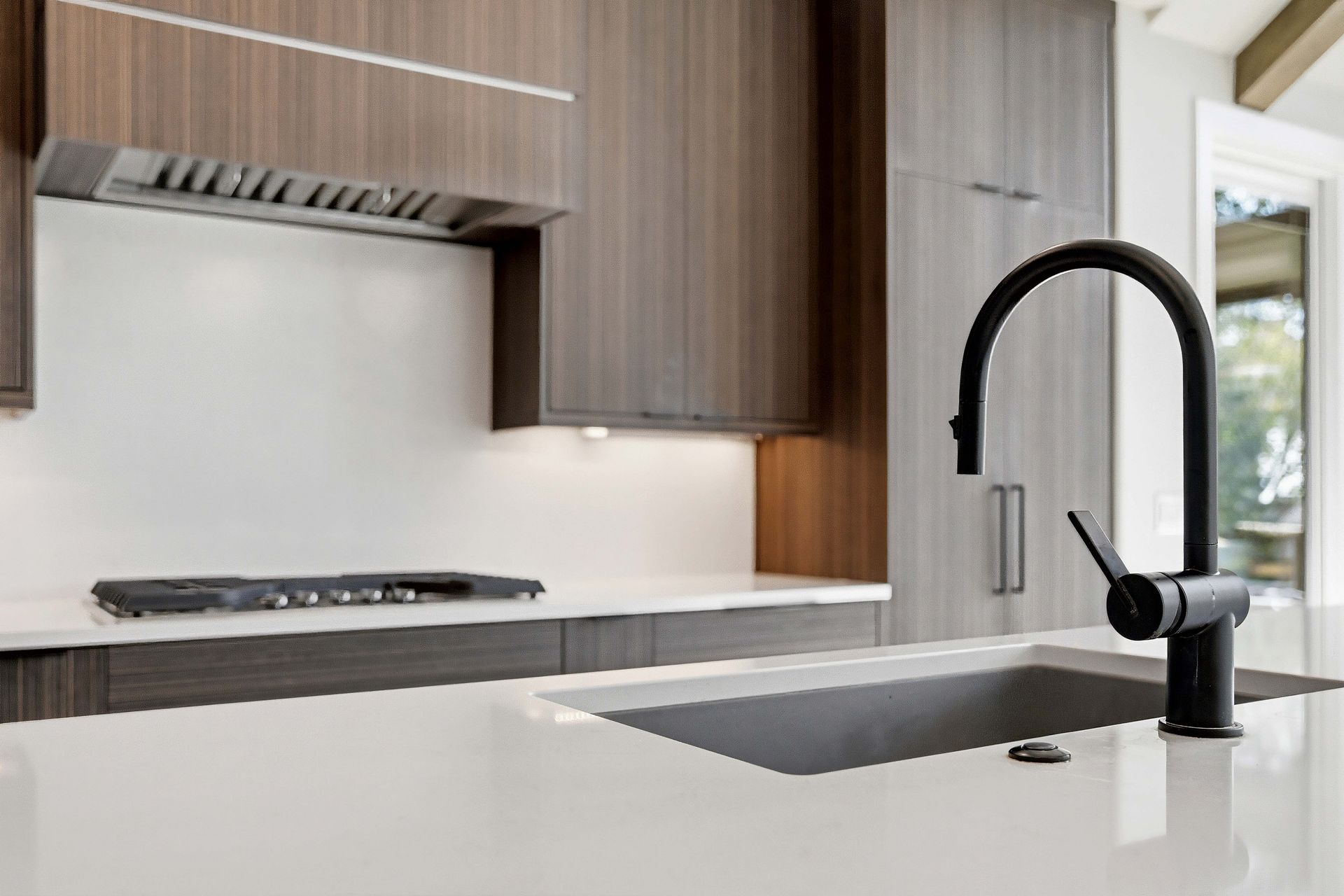 Modern kitchen with wood cabinets, white island, black faucet, and built-in stove