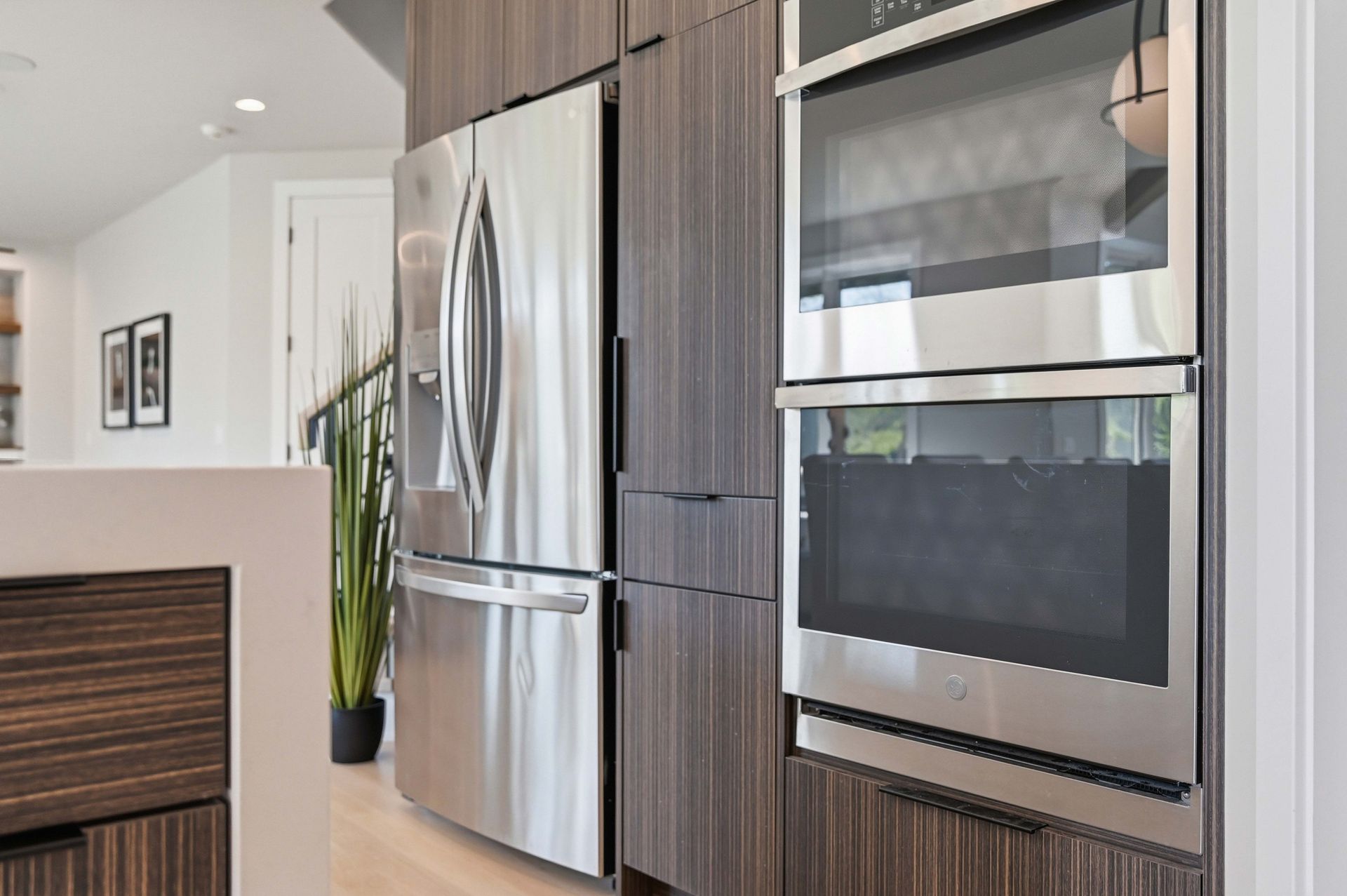 Modern kitchen with stainless steel fridge, built-in oven, and dark wood cabinets