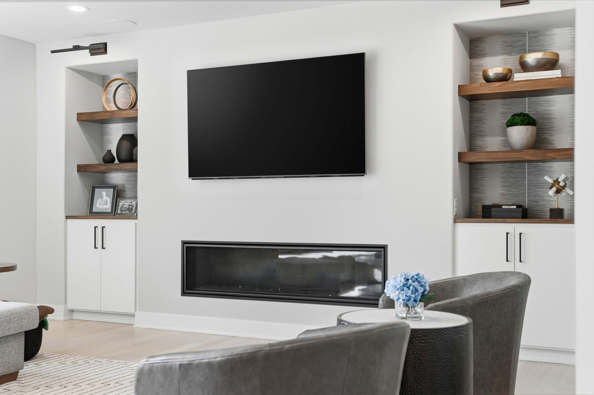 Modern living room with wall-mounted TV, fireplace, and built-in shelving with decor