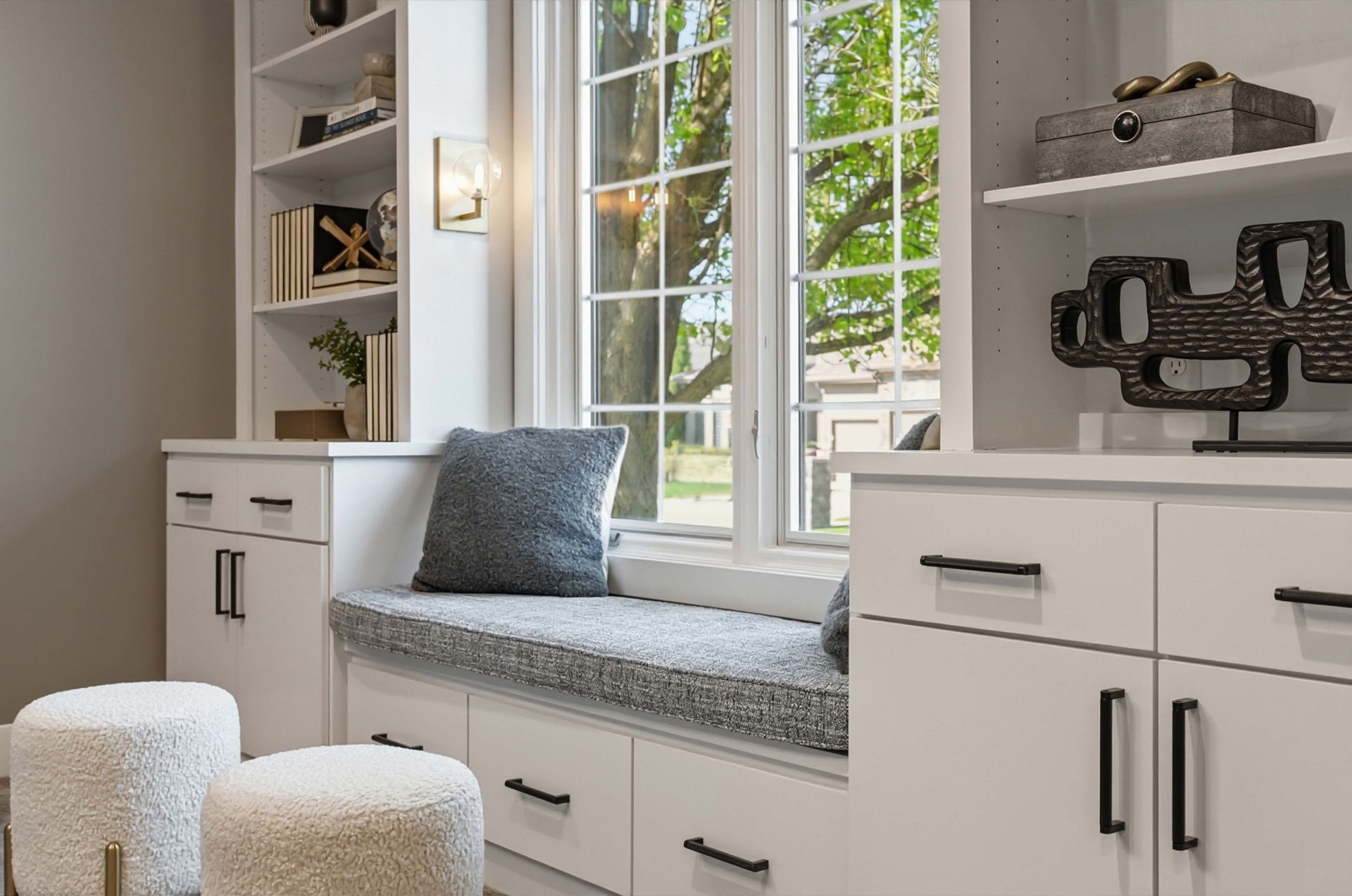 Bright home office nook with built-in bench, shelves, and a large window overlooking greenery
