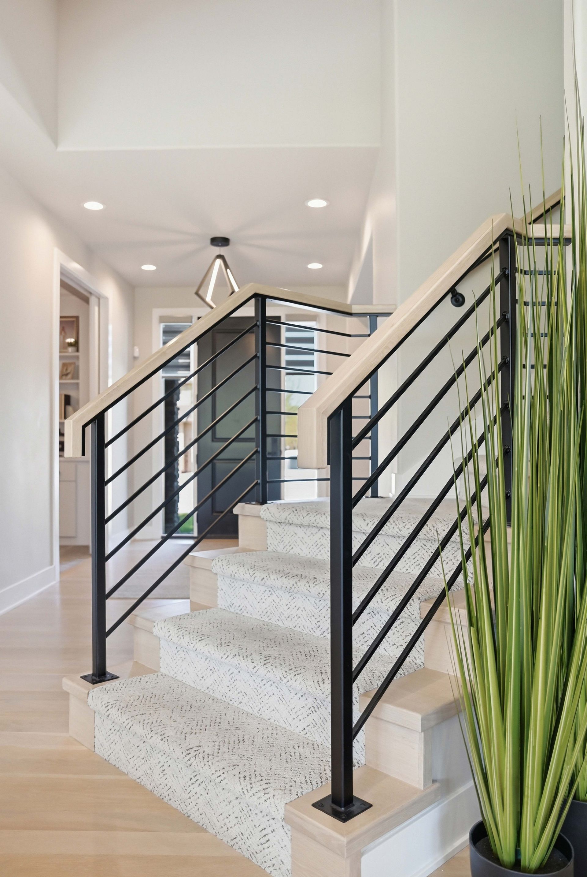 Modern stairway with black railings, white walls, and a tall potted snake plant in a bright hallway