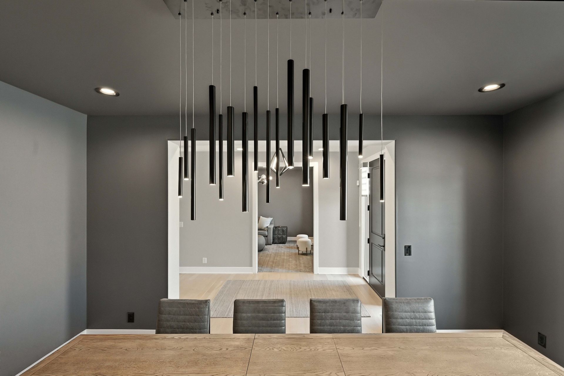 Modern dining room with a long table, gray chairs, and a black pendant light fixture.
