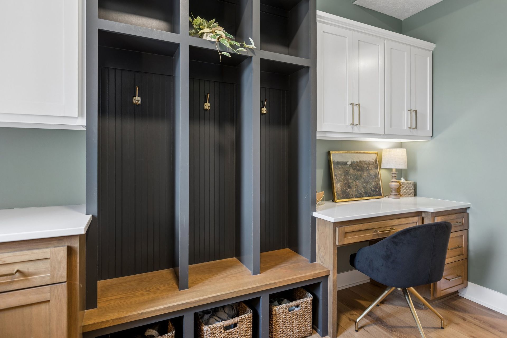 Built-in mudroom bench with cubbies, black doors, white cabinets, and a small desk with a chair.