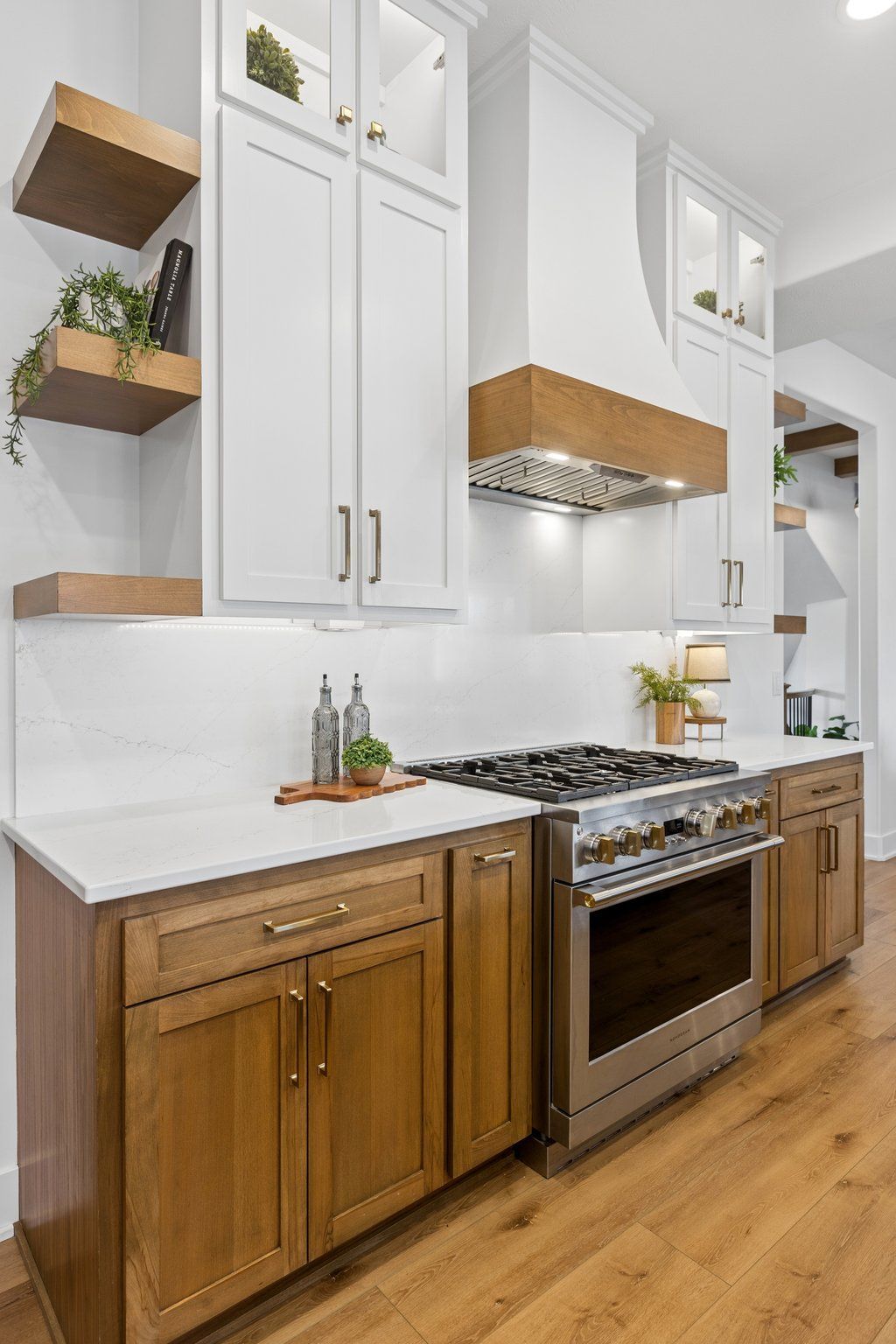 Modern kitchen with white cabinets, wood lower cabinets, stainless stove, and light wood flooring