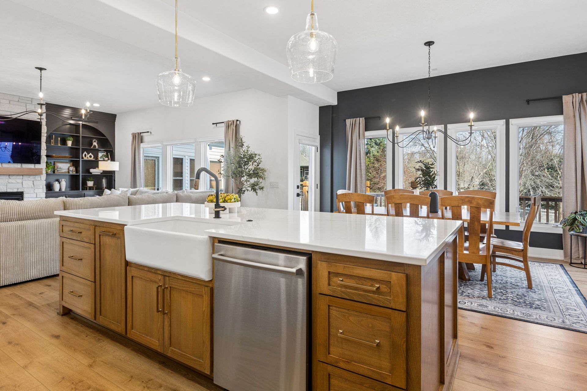 Bright open kitchen and dining area with island, stainless dishwasher, white countertops, and large windows