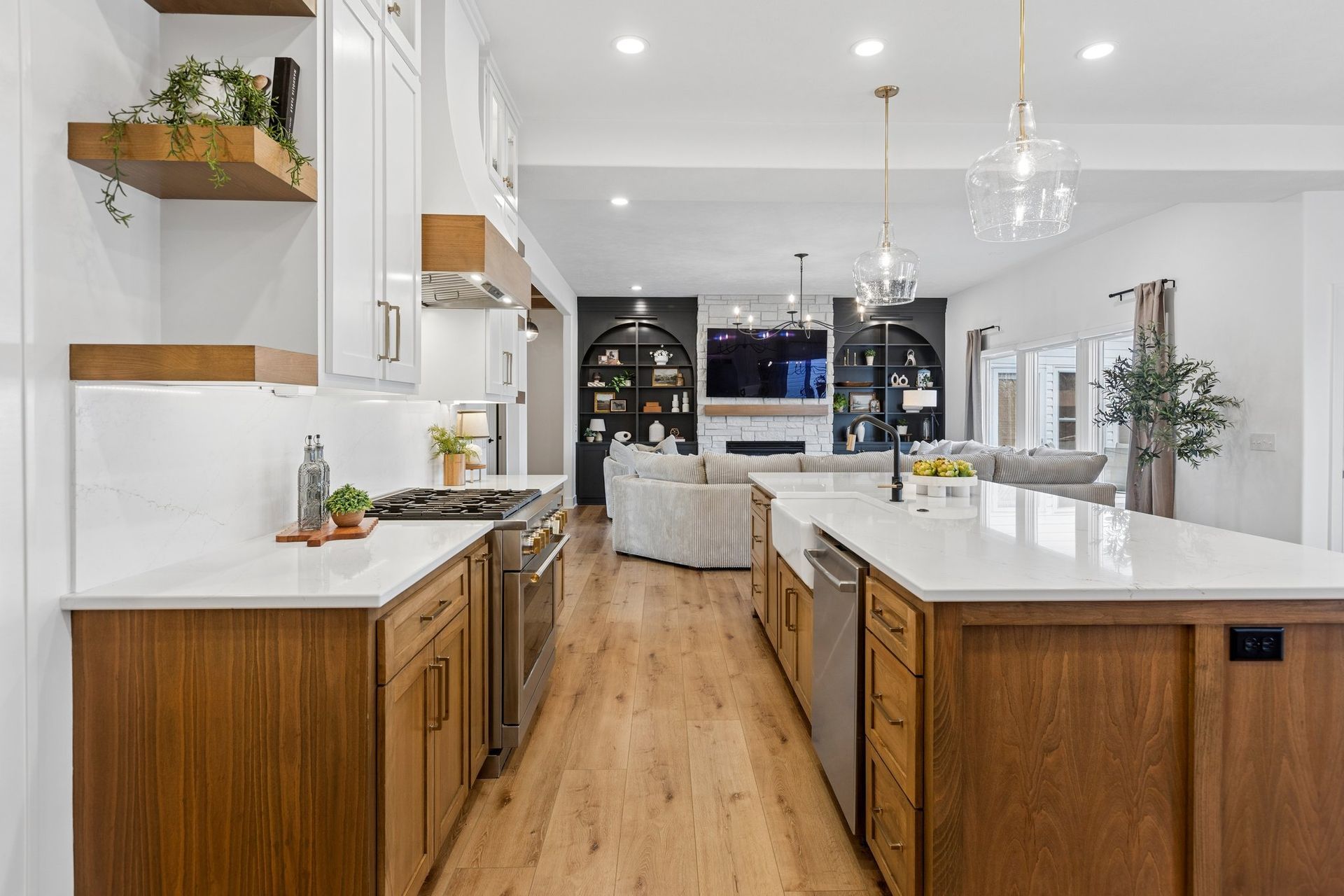 Modern kitchen with wood cabinets, white island, hardwood floors, and a view into a bright living room.