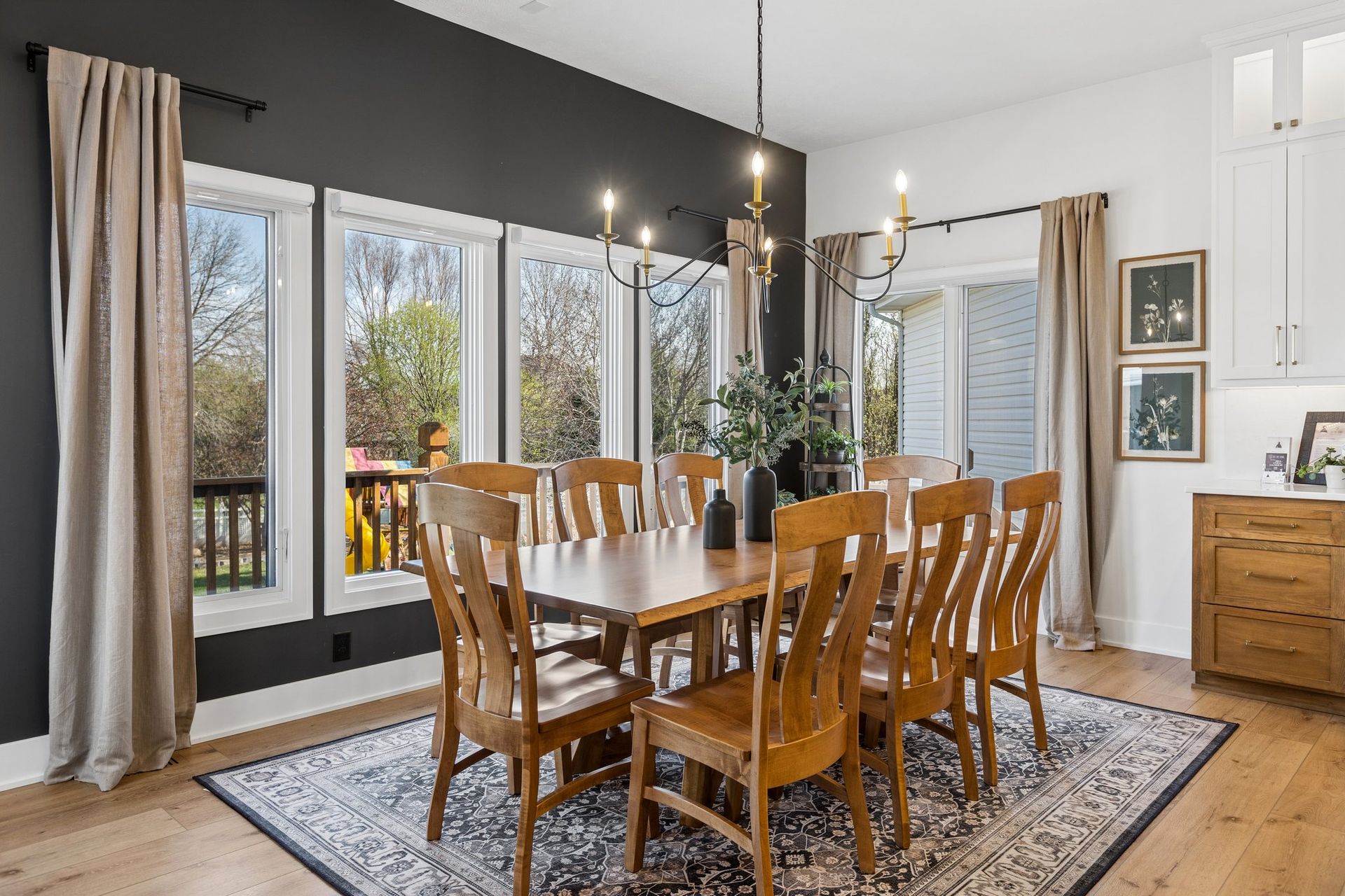 Bright dining room with wooden table, chairs, large windows, and neutral decor