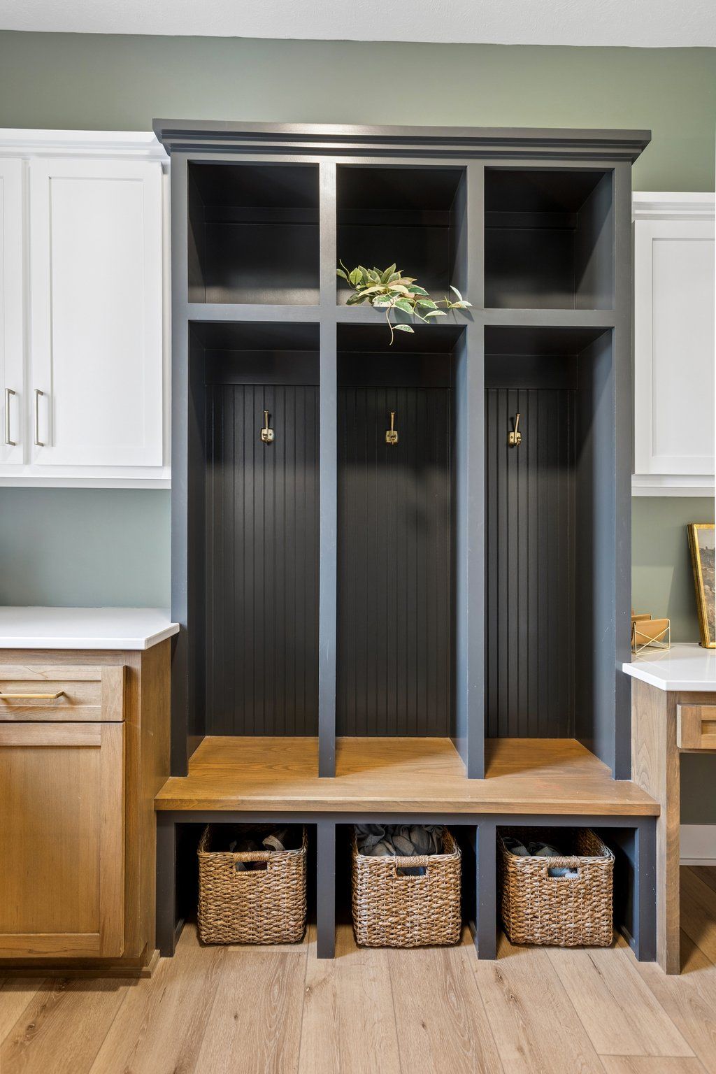 Built-in entryway cubbies with dark gray lockers, white cabinets, and woven storage baskets underneath