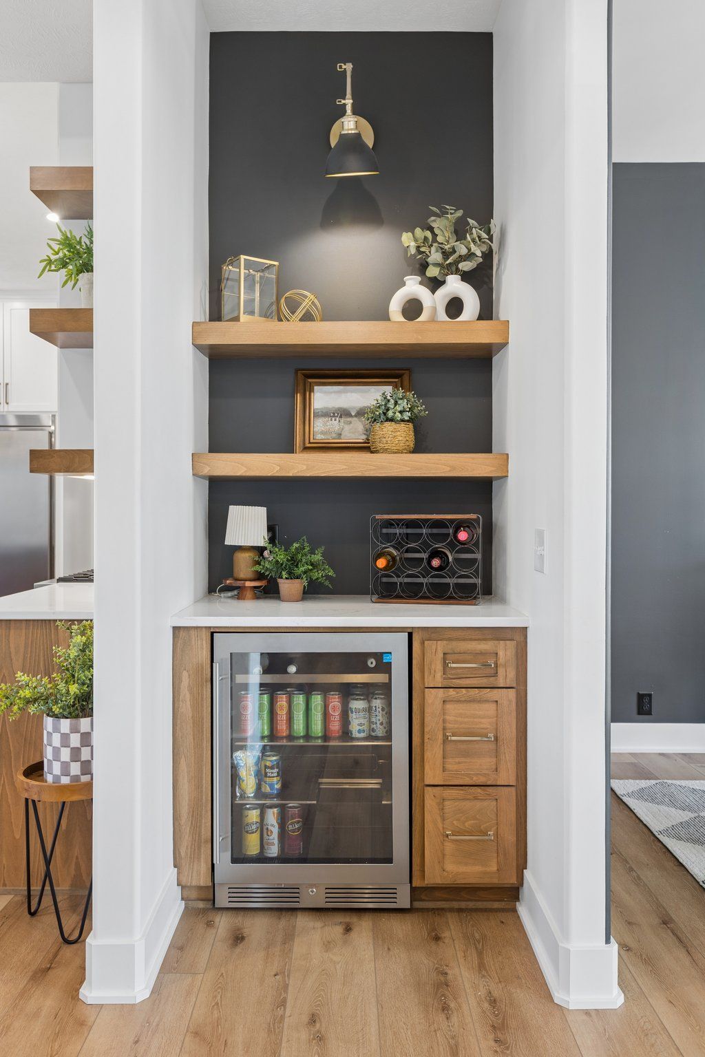 Built-in bar nook with wood shelves, wine cooler, and decor against a dark gray wall