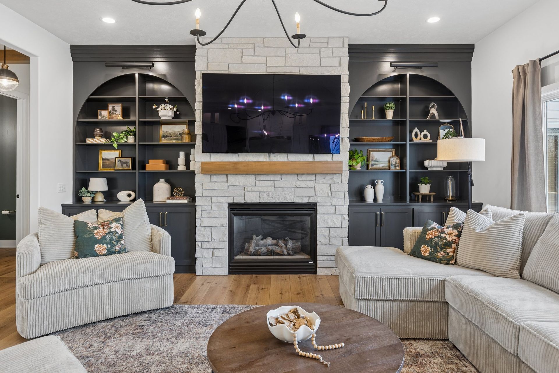 Modern living room with gray sectional, fireplace, built-in shelves, and wall-mounted TV