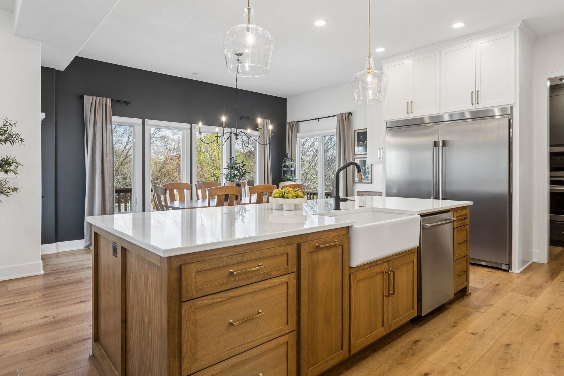 Modern kitchen with white island, wood cabinets, stainless appliances, and large windows