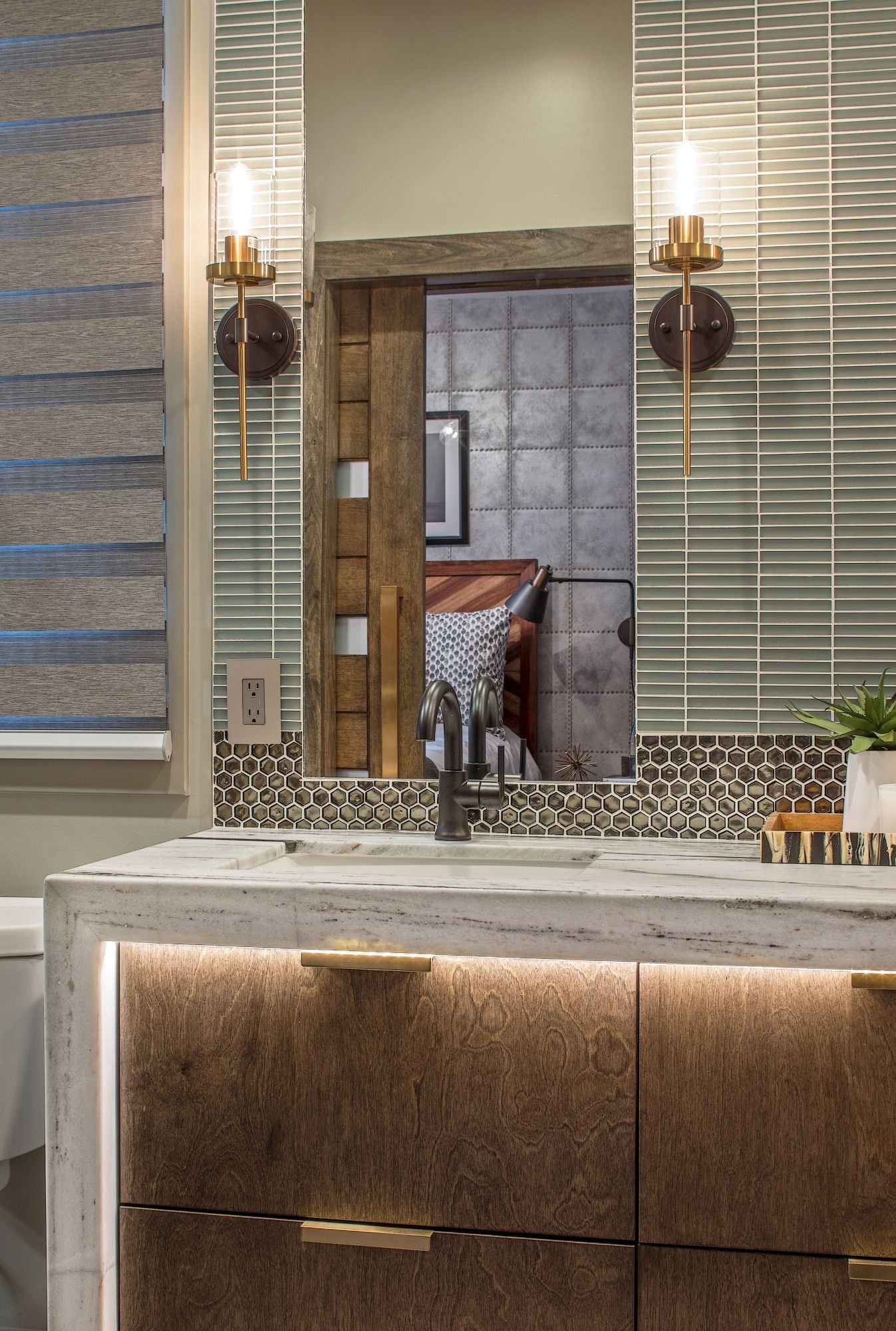 Bathroom vanity with mosaic tile mirror, wall sconces, and marble countertop