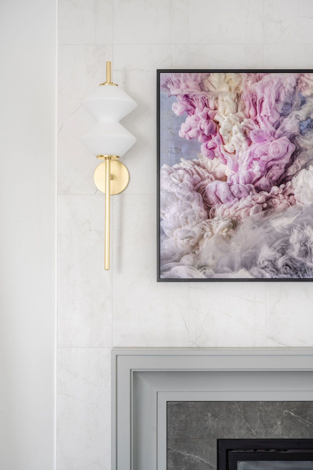 Gold wall sconce beside a pink abstract floral painting above a gray mantel