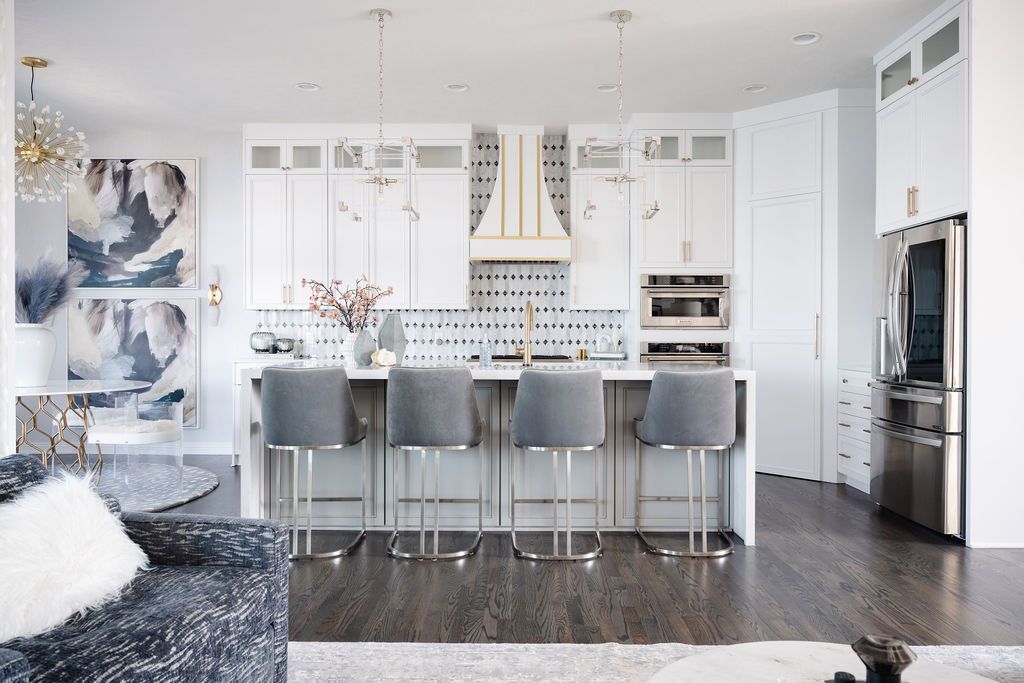 Bright modern kitchen with white cabinets, gray island stools, and stainless steel appliances