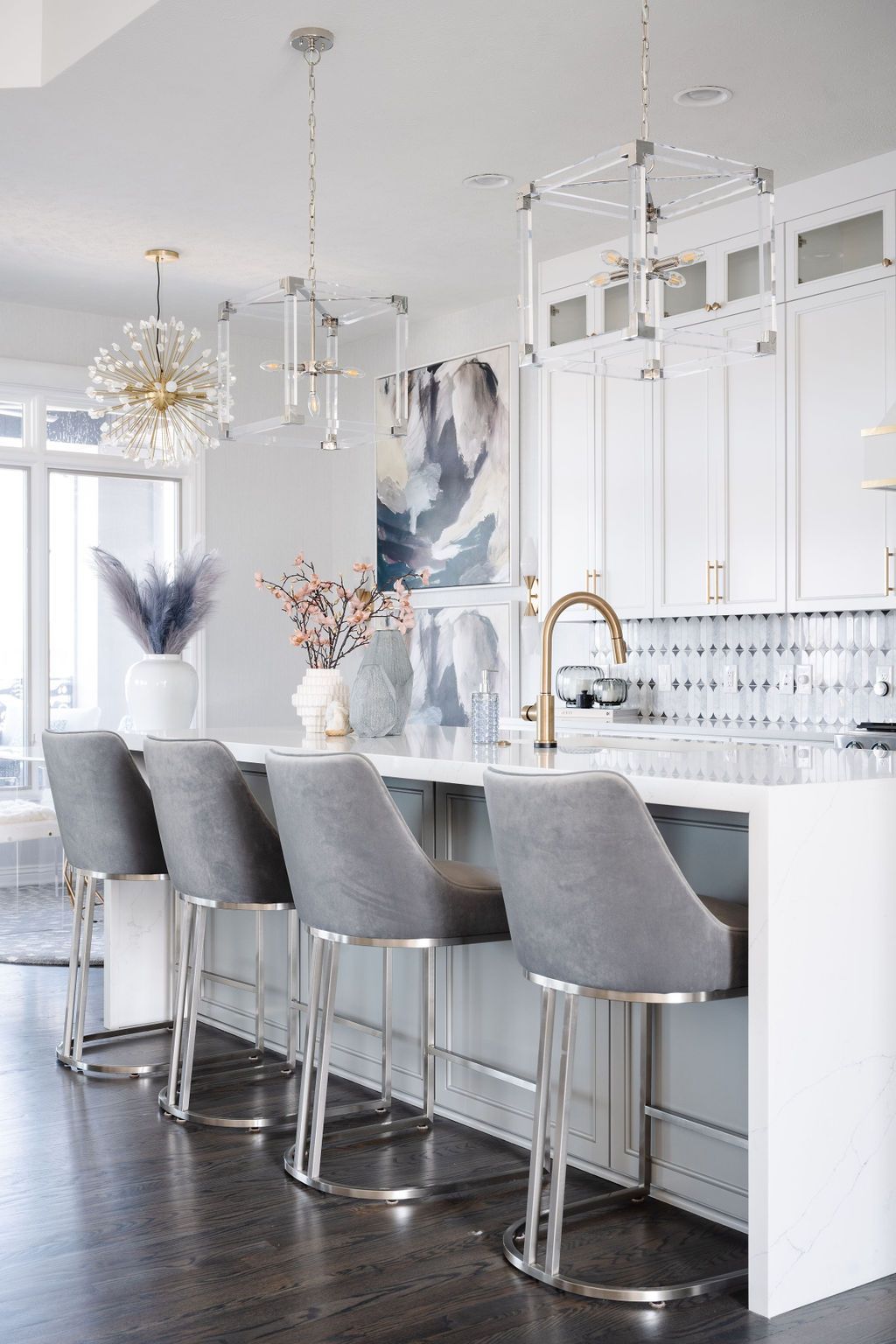 Modern white kitchen with a marble island, gray barstools, and pendant lights