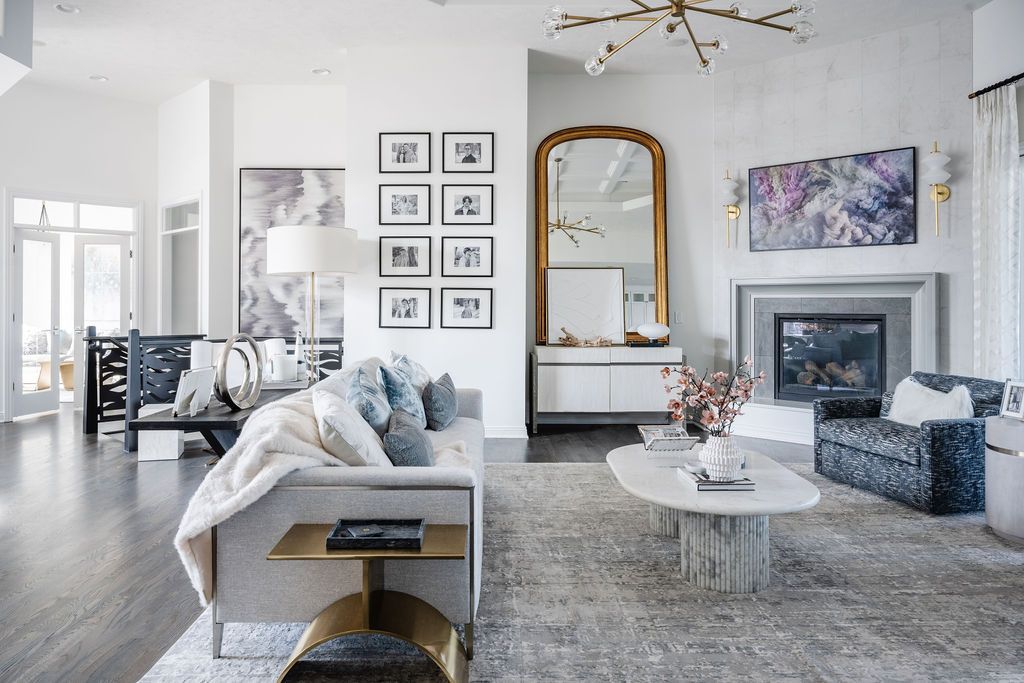 Bright modern living room with gray sofa, large mirror, fireplace, abstract art, and light wood flooring