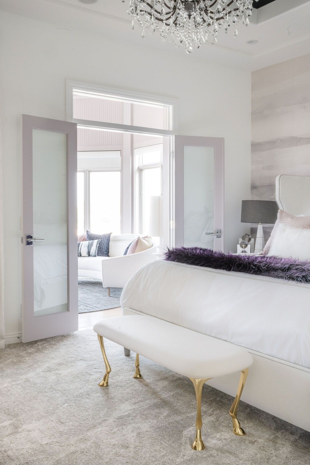 Bright white bedroom with open French doors, bed, bench, and soft gray decor