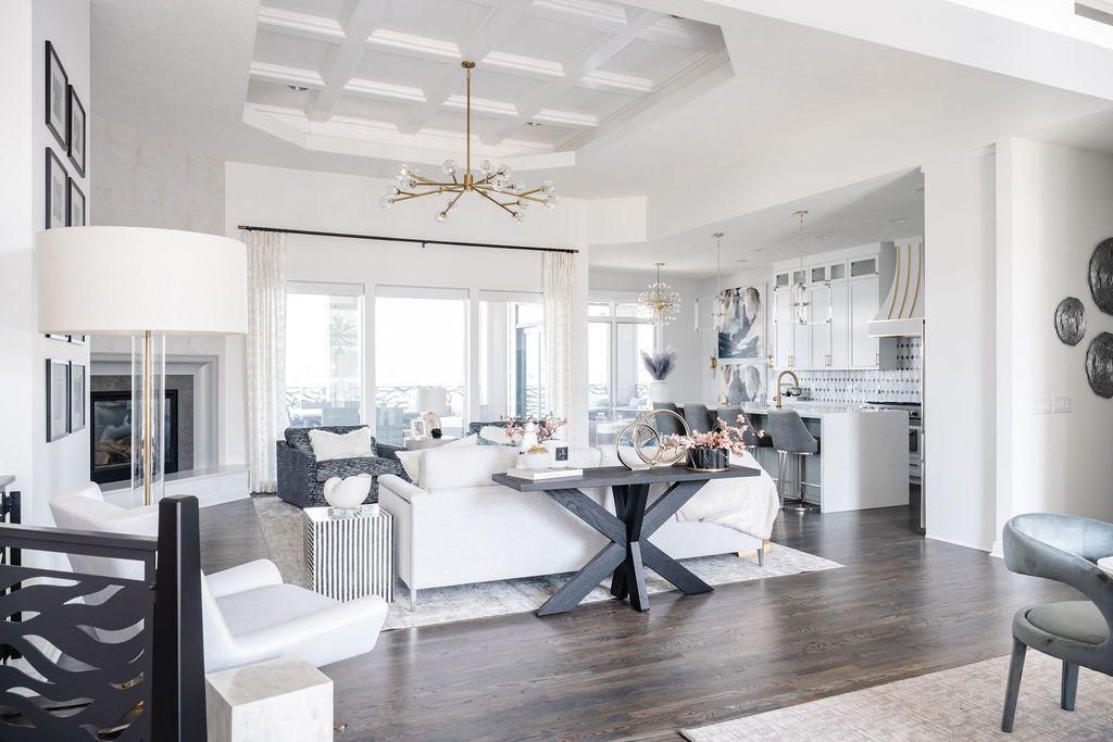 Bright, open living room with white furniture, chandelier, and dark wood floors.