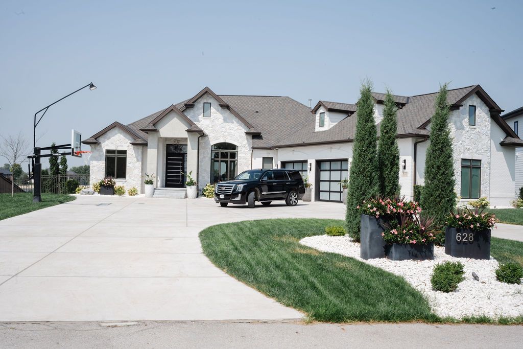Suburban house with a black SUV in the driveway and a curved lawn and flower bed in front