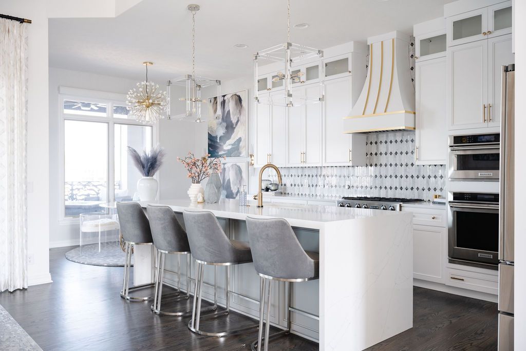Bright white modern kitchen with island, gray barstools, pendant lights, and glossy tile floor