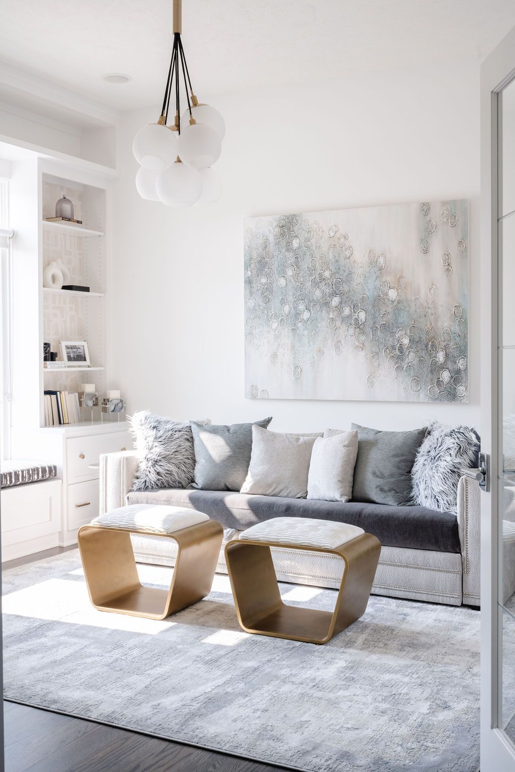 Bright modern living room with a gray sofa, abstract wall art, two wooden coffee tables, and a light rug