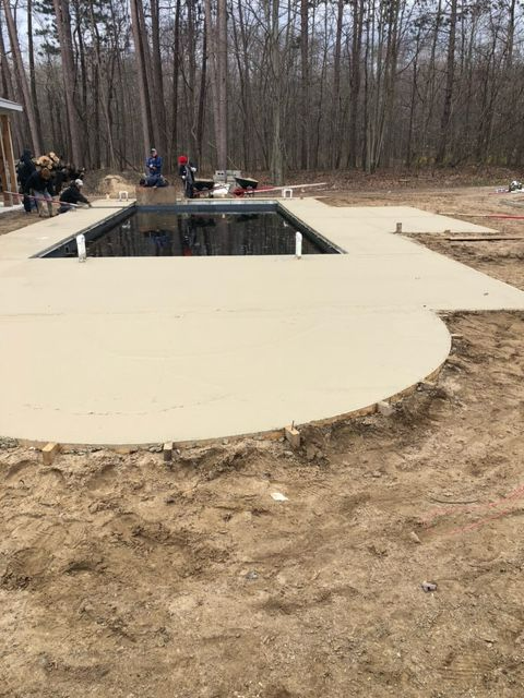 A swimming pool is being built in the middle of a dirt field.