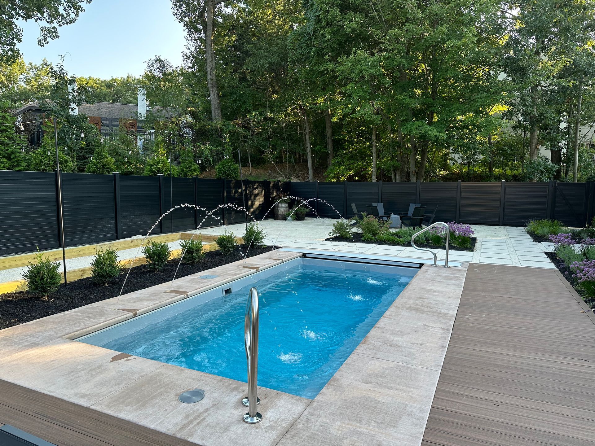 A small swimming pool in the backyard of a house surrounded by trees.