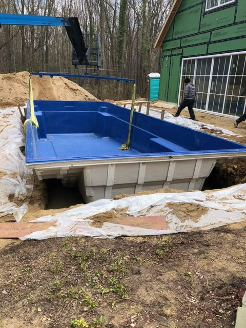 A large blue swimming pool is being built in front of a house.