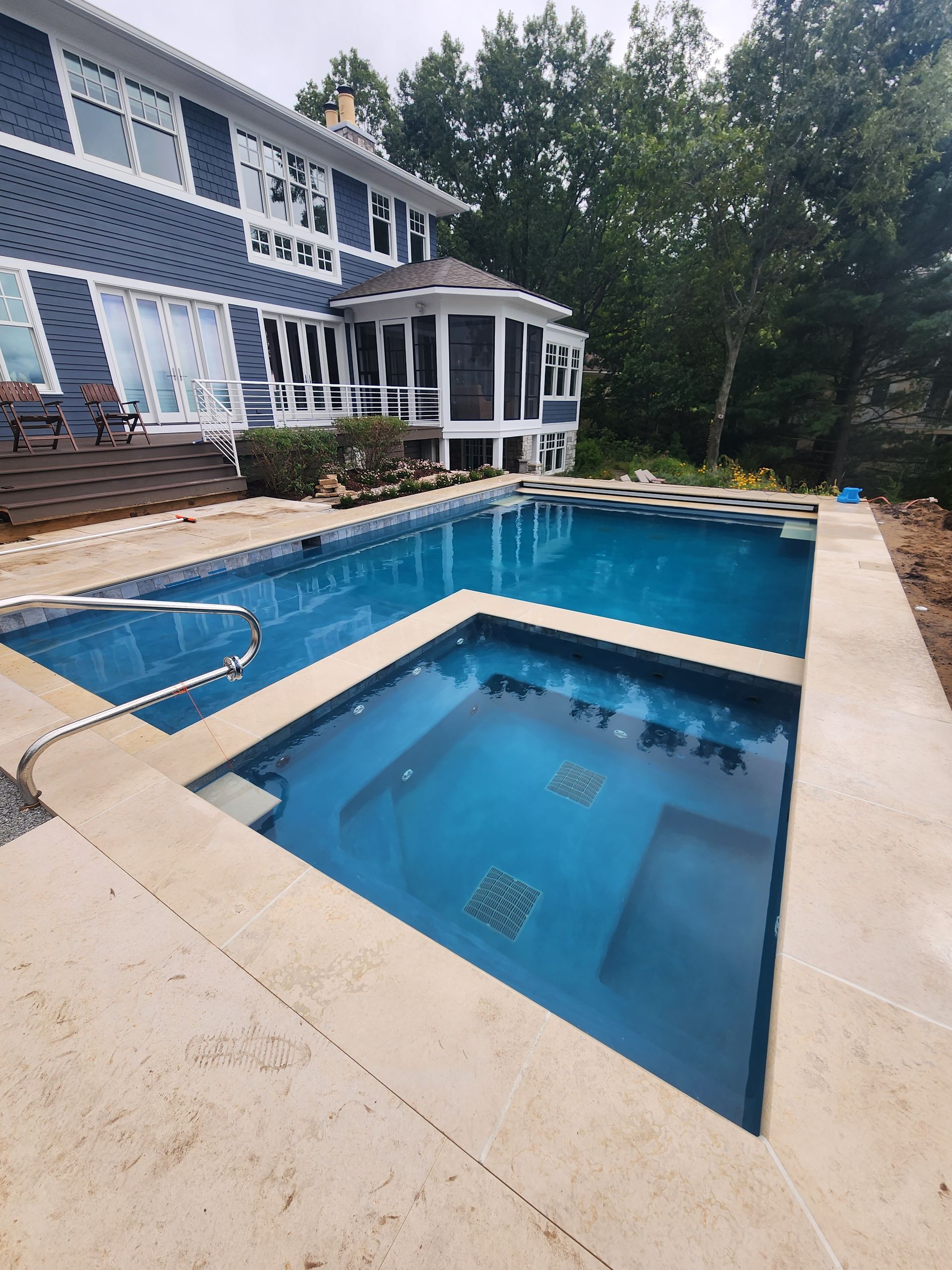 A large swimming pool with a hot tub in front of the house.